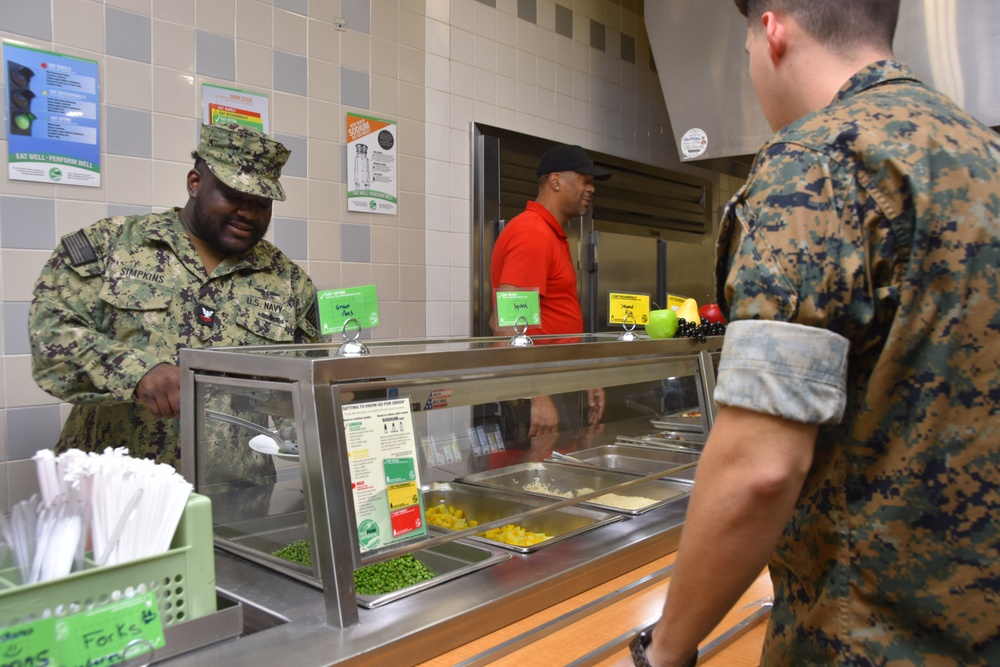 Culinary Specialist 2nd Class Bradley Simpkins, left, assigned to Naval Air Station (NAS) Joint Reserve Base (JRB) Fort Worth serves food at the Moreland Dining Hall facility onboard NAS JRB Fort Worth.