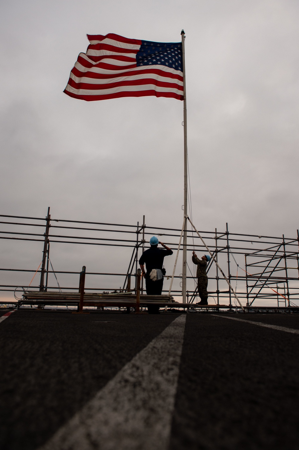 Sailors lower the ensign on the flight deck of Nimitz-class aircraft carrier USS Carl Vinson