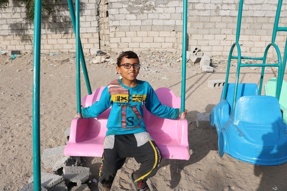 A child enjoys playground equipment in Al Shouhada, Yemen