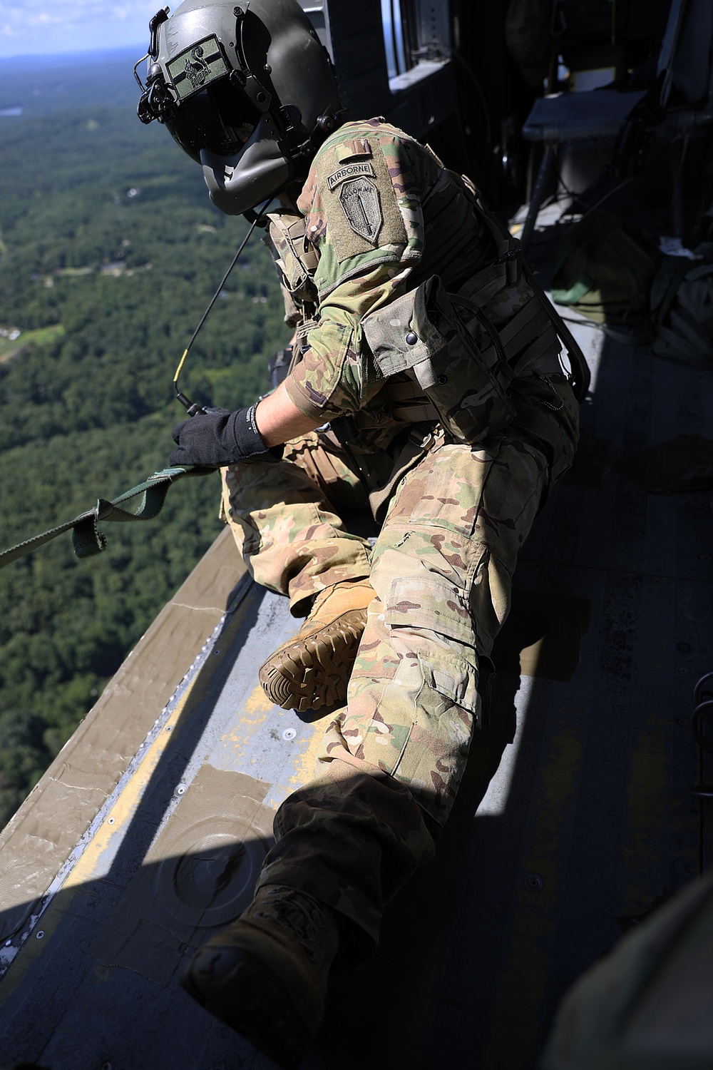 US Army helicopter crewmember looks out over the drop zone