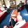 Three military personnel in uniform are seated in a formal office setting, engaged in what appears to be a meeting or discussion. The room is well-appointed with red leather furniture, a wooden coffee table, bookshelves, and various military memorabilia and flags. The individuals wear different national military uniforms, suggesting an inter-military or multinational meeting.