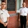 Two military officers in uniform stand on either side of a commemorative bronze plaque mounted on a brick wall. The plaque honors Walter Reed (1851-1902), a Major in the U.S. Army Medical Corps described as 'Soldier, Physician, Teacher, Scientist.' The setting appears to be a historic building associated with Walter Reed's legacy.