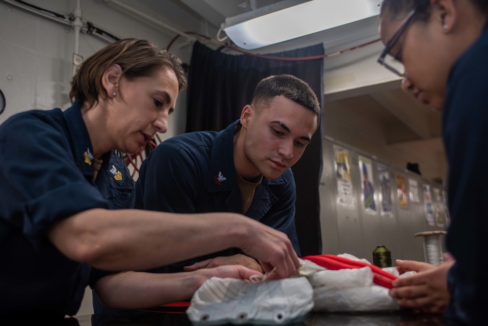 USS Ronald Reagan (CVN 76) Sailors pack and prepare parachutes