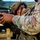 1-68 AR conducts an Abrams platoon live-fire exercise Two soldiers in U.S. Army OCP (Operational Camouflage Pattern) uniforms are handling what appears to be a weapon system or launcher with a visible safety warning label reading 'READ BEFORE FIRING.' The foreground soldier displays a unit patch on the shoulder consistent with the 4th Infantry Division. The setting appears to be an outdoor training or operational environment.