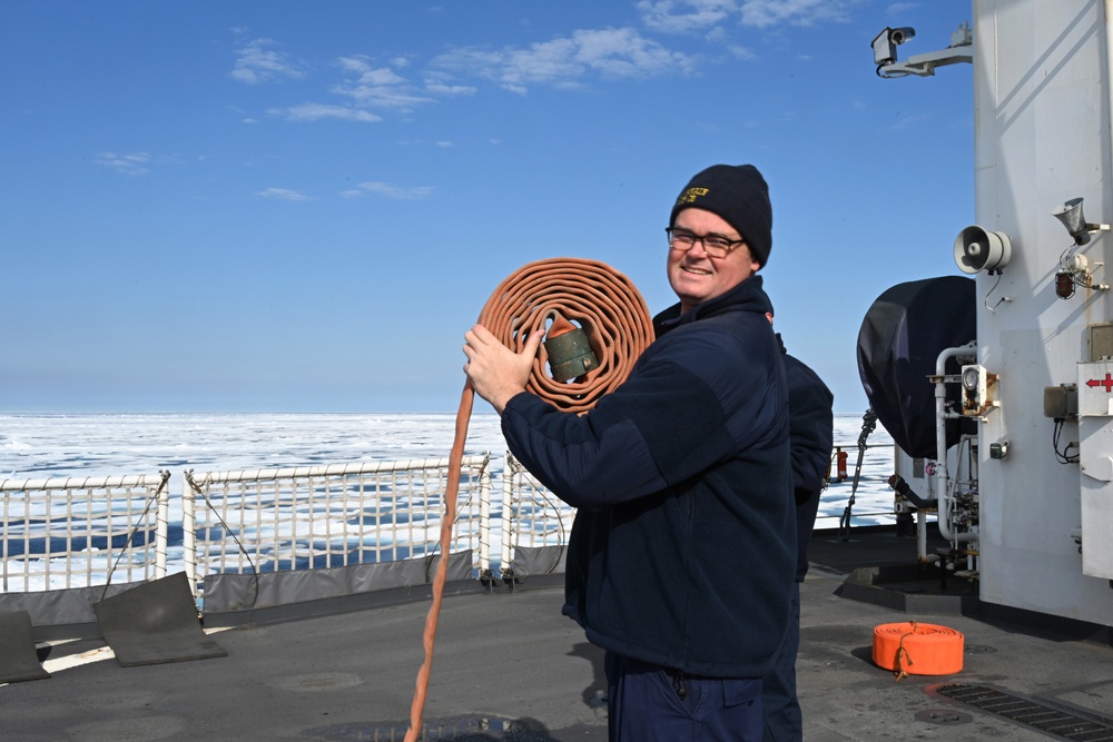 Coast Guard Cutter Healy crewmember stowing firehose