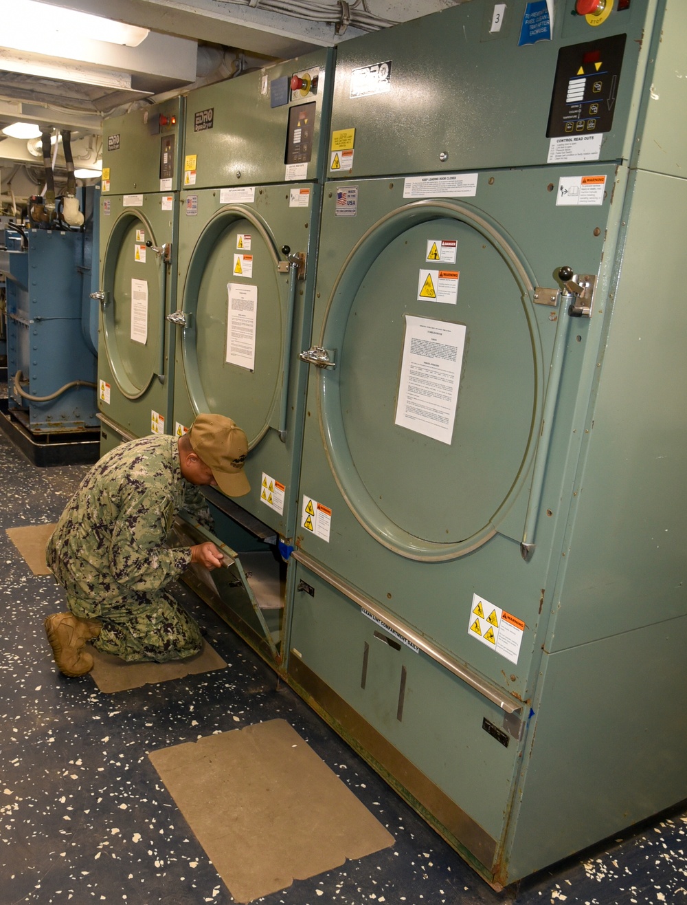 Petty Officer Third Class Joseph Rafael examines at the dryer vent to ensure it is functioning properly during the full management review on aboard the USS Germantown on Aug 31. 2022.