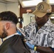 Seaman Martin Blake cuts Petty Officer Third Class Kevin Strader's hair during the full management review on aboard the USS Germantown on Aug 31. 2022.