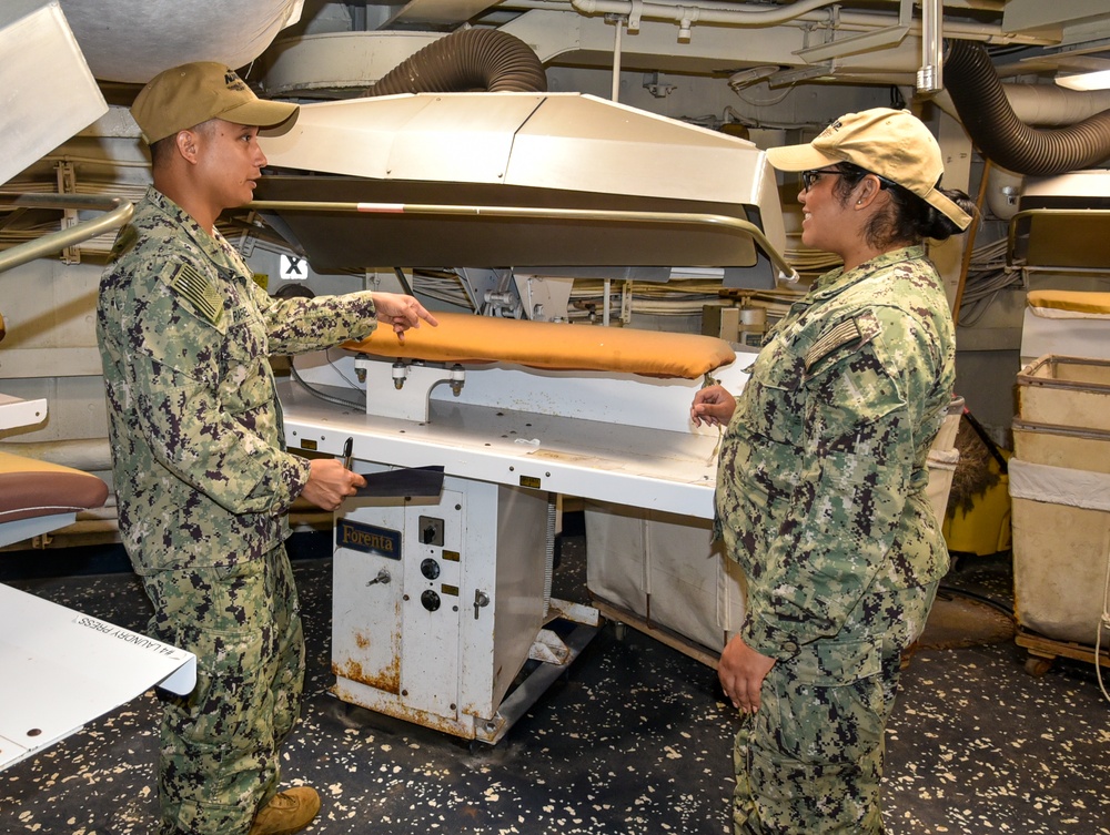 The Fleet Assistance Team inspects the laundry press to ensure it is in proper working condition during the full management review on aboard the USS Germantown on Aug 31. 2022.