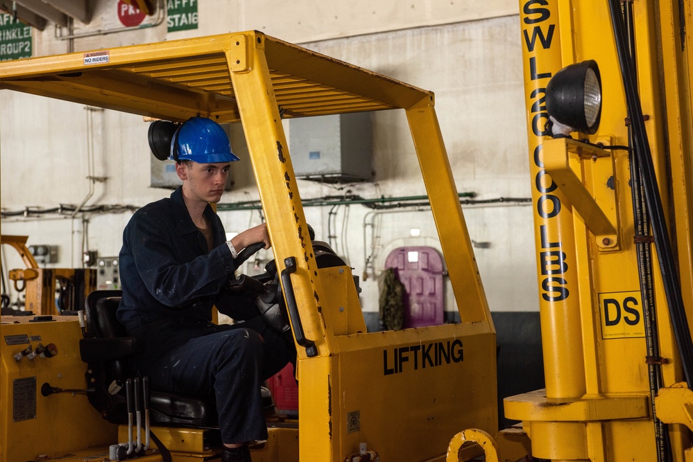 USS Ronald Reagan (CVN 76) Sailors on load cargo in hangar bay