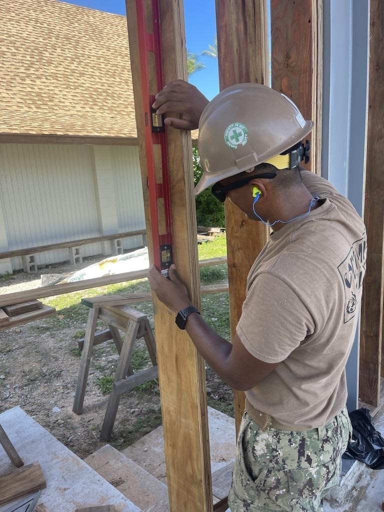 Builder 3rd Class Darren Levine, ensures a wall stud is level on the Richardson Multipurpose Facility .
