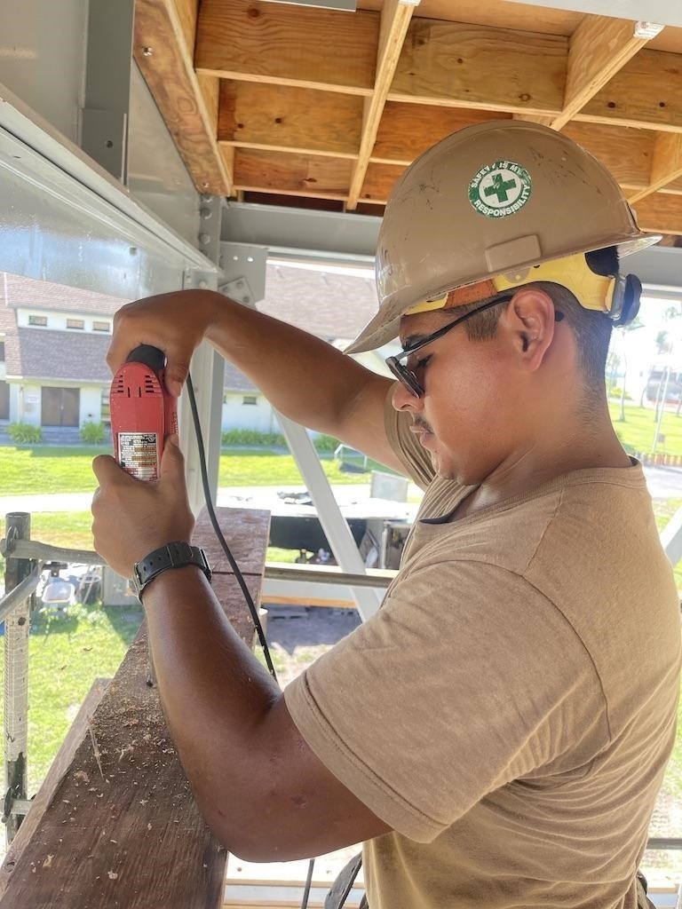 Builder 3rd Class Carlos Hernandez, drills holes in nailing boards for the Richardson Multipurpose Facility.
