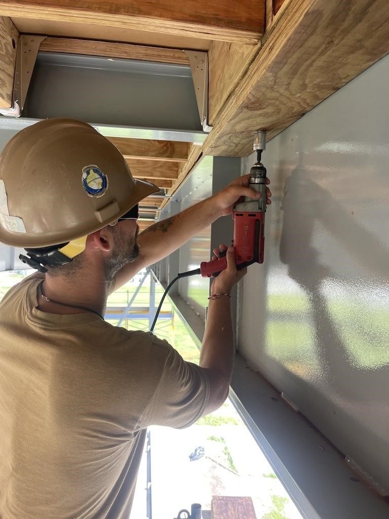 Builder 2nd Class Stephen Tritsch, secures nailers to the steel frame of the Richardson Multipurpose Facility.