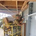 Equipment Operator 3rd Class Francisco Ramirez and Steelworker 3rd Class Daniel Ceren, install steel fascia on the Richardson the Multipurpose Facility.