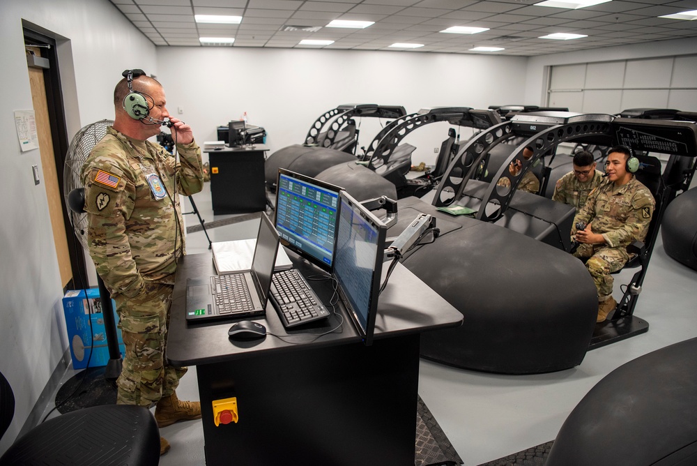 U.S. Army Staff Sgt. Matthew Ellis, Charlie Company, 1-210th Aviation Regiment, 15N Avionics Mechanic Instructor, communicates with students using headsets during a hands-on training session.