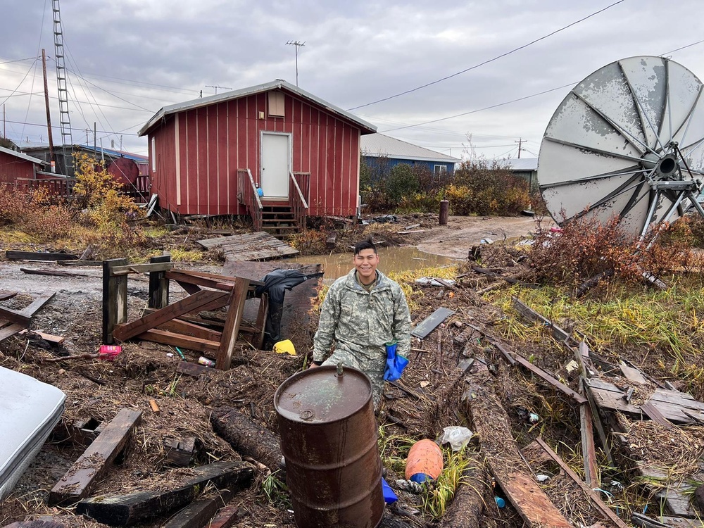 A service member of the Alaska Organized Militia clears storm debris for Operation Merbok Response