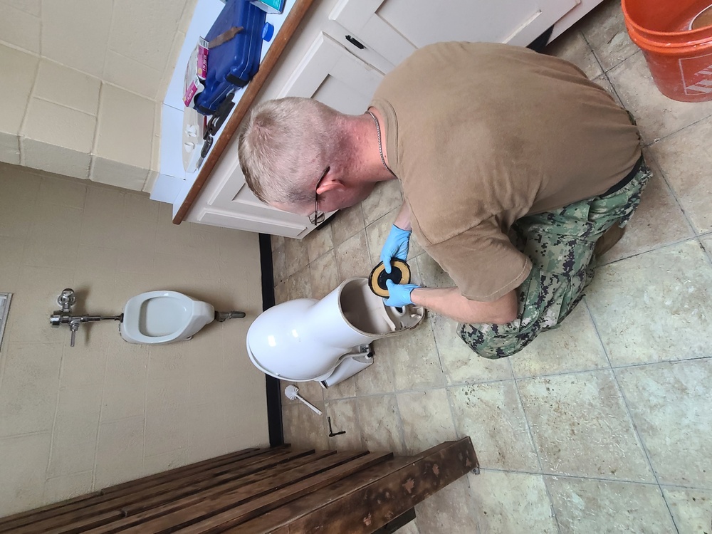 Seabee installs wax rings on toilets in support of camp maintenance shop