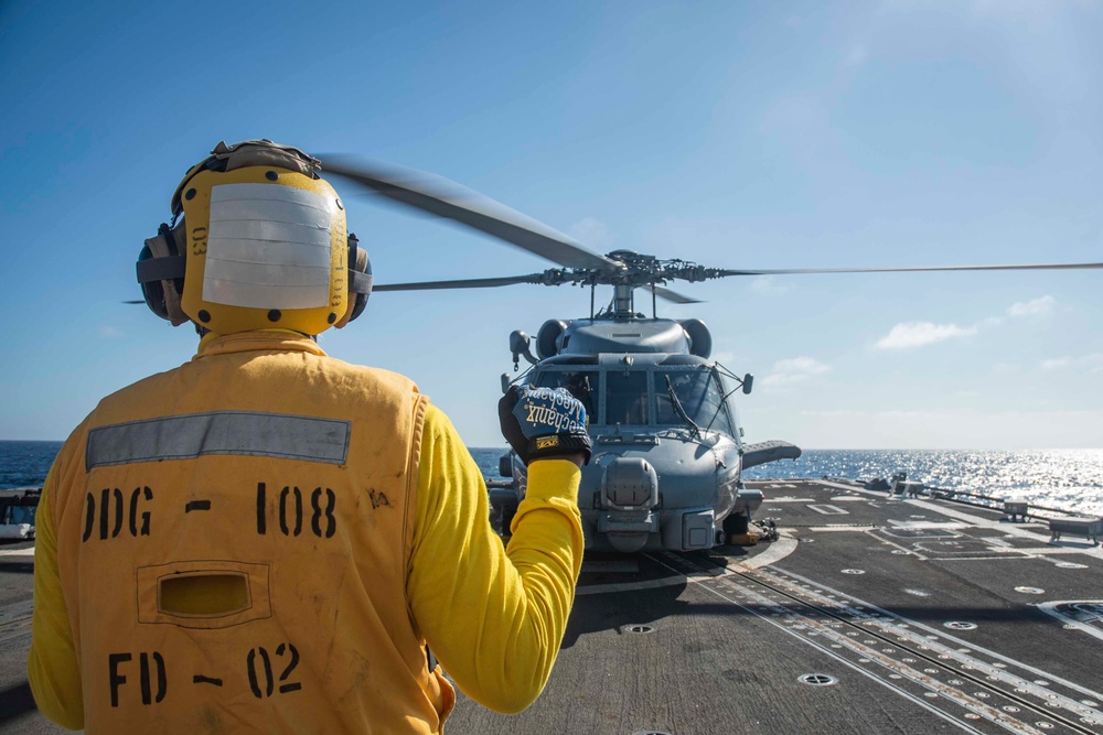 U.S. Sailor Directs An MH-60R Sea Hawk Helicopter