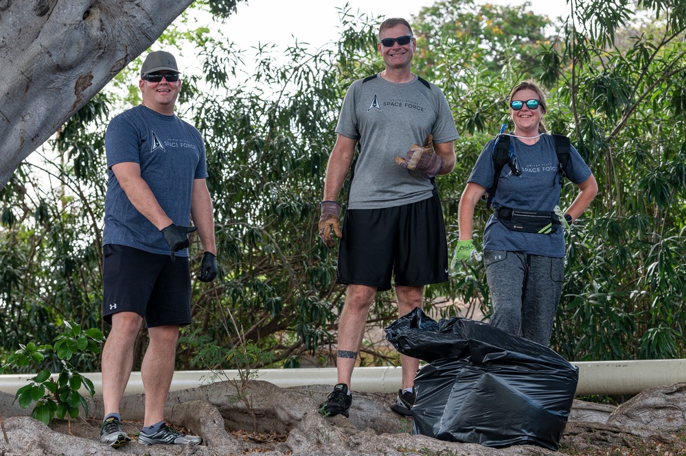 U.S. Space Force Lt. Col. Walter Priebe III, Pacific Air Forces deputy  director of Space Force, picks up trash along a road during a base cleanup  event Sep. 23, 2022, at Joint