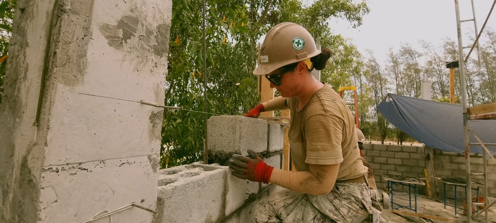 Steel Worker 3rd Class Kacianne Mcdaniel, lays a course of Concrete Masonry Units block.