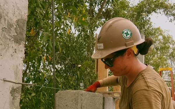 Steel Worker 3rd Class Kacianne Mcdaniel, lays a course of Concrete Masonry Units block.