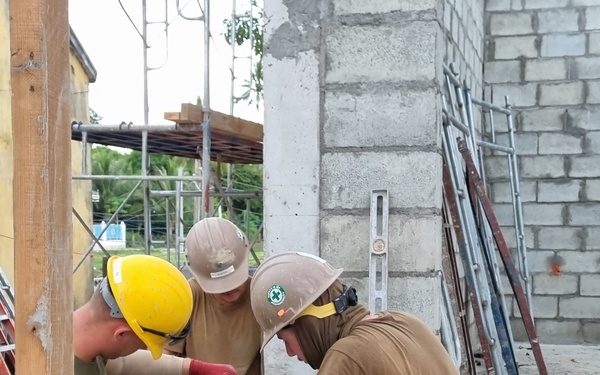 Seabees and Marines level a course of Concrete Masonry Units block for the Phước Hòa primary school in Vietnam.