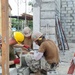 Seabees and Marines level a course of Concrete Masonry Units block for the Phước Hòa primary school in Vietnam.