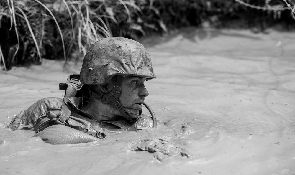 Lt. Bradley Revenis moves through murky waters while completing The Jungle Warfare Training Course.