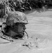 Lt. Bradley Revenis moves through murky waters while completing The Jungle Warfare Training Course.