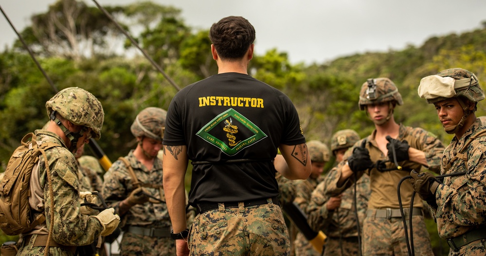 Seabees and Marines prepare to cross rope bridges during Jungle Warfare Training.