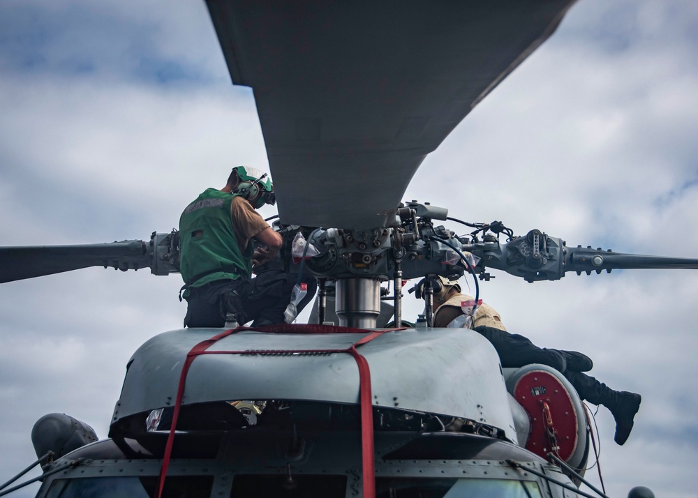 U.S. Sailors Conduct Routine Maintenance On An MH-60R Sea Hawk Helicopter