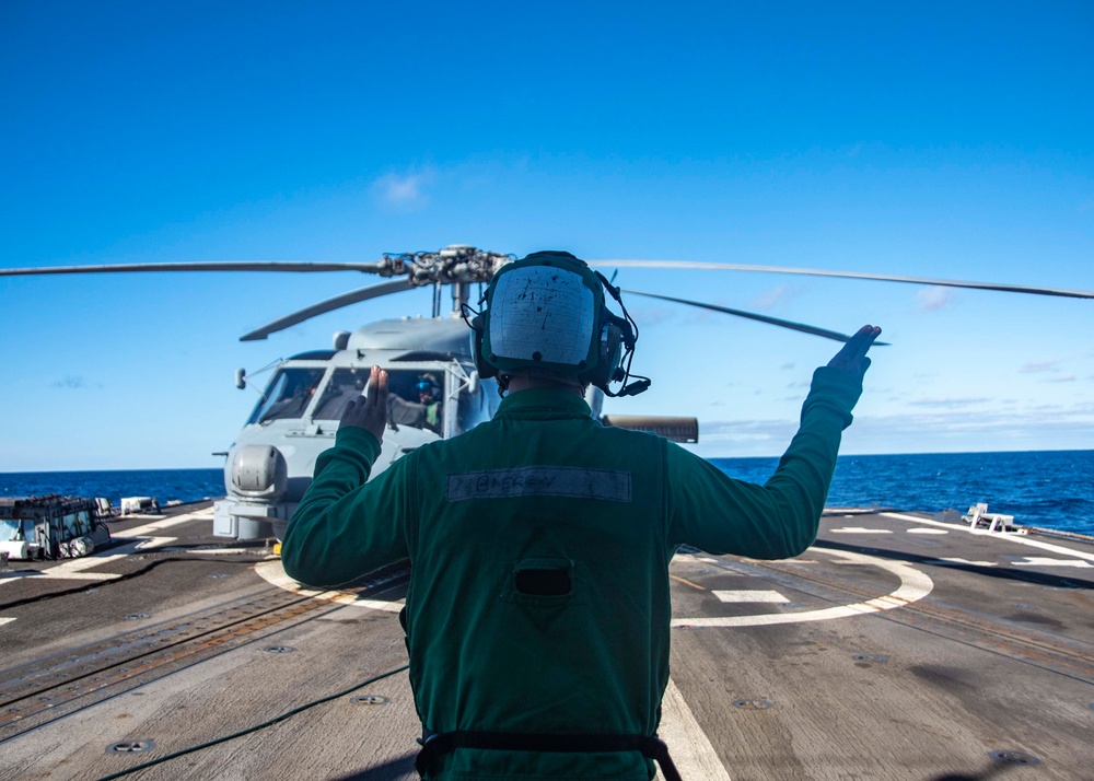 U.S. Sailor Directs An MH-60R Sea Hawk Helicopter