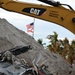 A Flag Blows in the Wind in Front of a Debris Pile