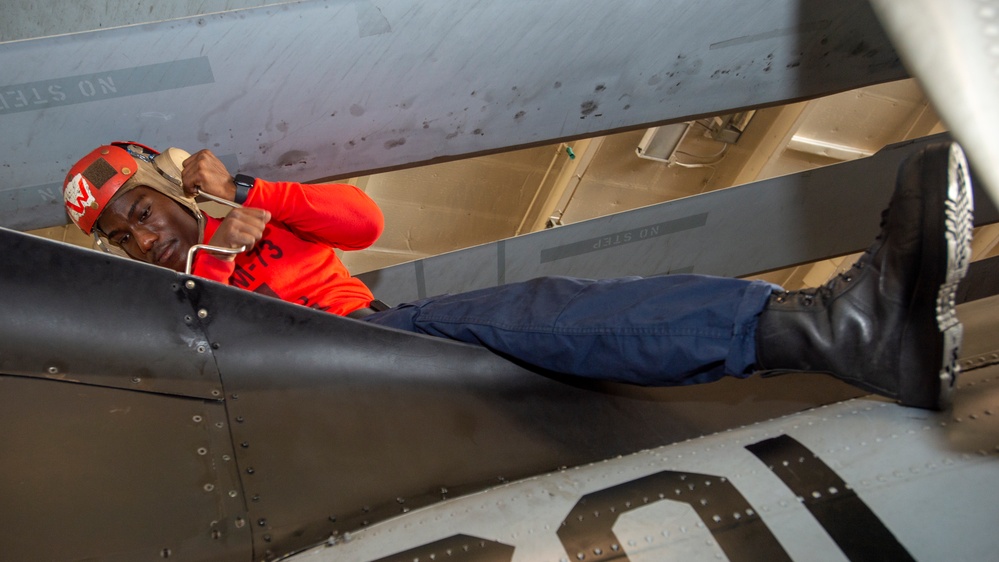 Sailor Removes Bolts From Aircraft