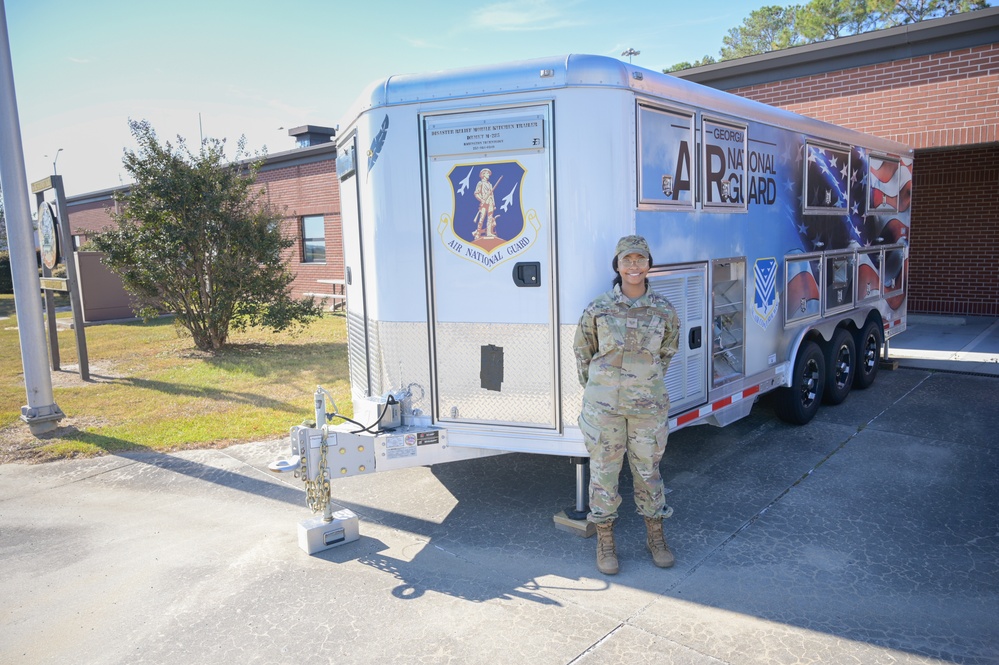 Photo of 116th Services Airman by disaster relief mobile kitchen trailer