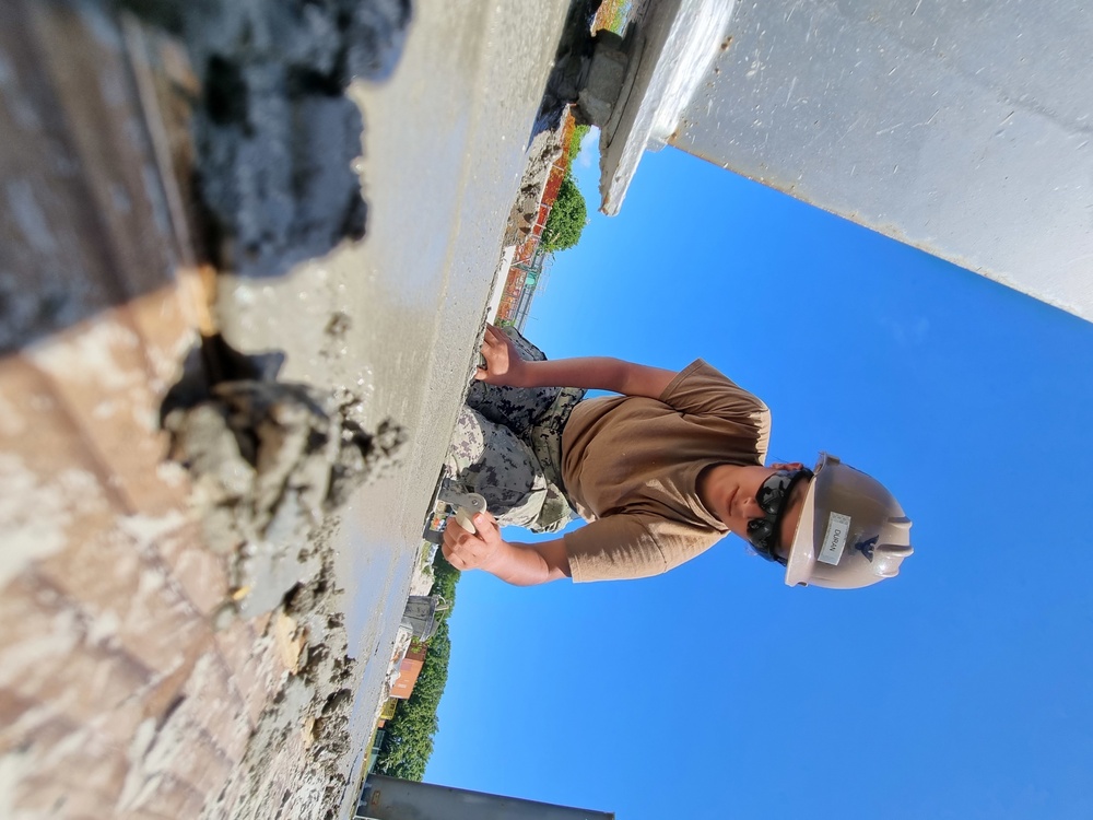 Utiliesman 2nd Class Joane Duran, spreads concrete that will ultimately support the wall panel.