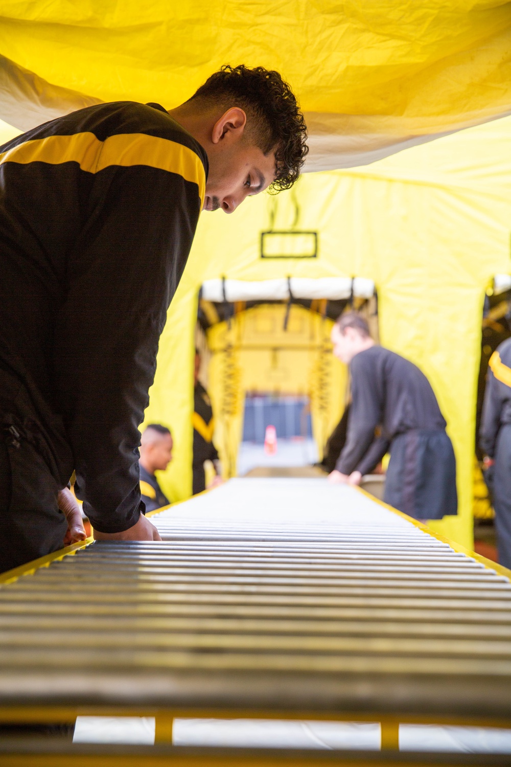 Solider from 138th Chemical Company connects roller tables for Exercise Vista Forge