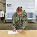 Capt. Cory Schemm, commanding officer NAVSUP FLC San Diego, signs the commissioning documents for the Modula Vertical Lift Modules.