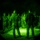 TACP Lightning Challenge 2022 A night vision image showing a group of military personnel gathered in a circular formation outdoors at night. Two individuals in civilian-style dark clothing appear to be addressing or briefing a larger group wearing camouflage uniforms. The circular vignette and green monochromatic tones are characteristic of night vision optics.