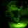 TACP Lightning Challenge 2022 A night vision image showing a military personnel in camouflage uniform examining or working with equipment on a surface illuminated by a green light source. The circular vignette effect is characteristic of imagery captured through night vision optics. The soldier appears to be handling a small device while referencing what appears to be a map or document.