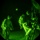 TACP Lightning Challenge 2022 A night vision image captured through what appears to be a night vision device, showing two military personnel in full combat gear during a nighttime operation. The characteristic circular vignette and green monochromatic tones confirm this was captured through night vision optics. One soldier appears to be boarding or exiting a military vehicle while another stands nearby.