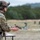 TACP Lightning Challenge 2022 A military or law enforcement operator in full tactical gear is handling a semi-automatic pistol at what appears to be an outdoor shooting range. The individual is wearing multicam camouflage, a tactical helmet with accessories, and hearing protection. The background shows a range environment with targets and other personnel visible in the distance.