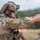 TACP Lightning Challenge 2022 A military or law enforcement operator in full tactical gear is firing a semi-automatic pistol at a shooting range. A spent brass casing is visibly ejecting from the firearm, indicating the weapon has just been discharged. Additional personnel are visible in the background, suggesting a supervised training exercise.