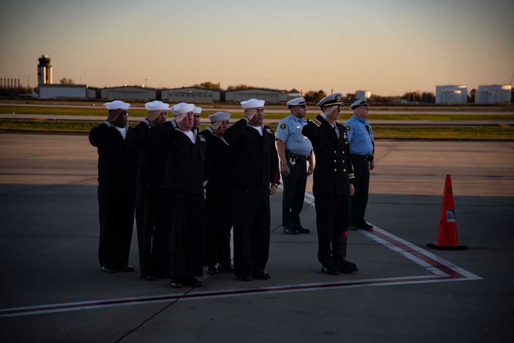 Sailors salute an aircraft containing the remains of RM3 Charles Montgomery.