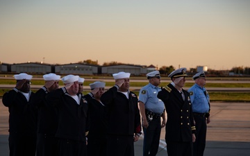 Sailors salute an aircraft containing the remains of RM3 Charles Montgomery.