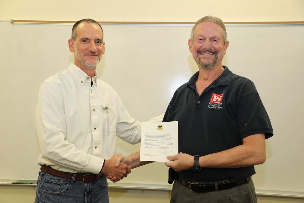 Huntsville Center employee Allyn Allison receives a Commander's coin and 3-star note in honor of his 21 years of service.