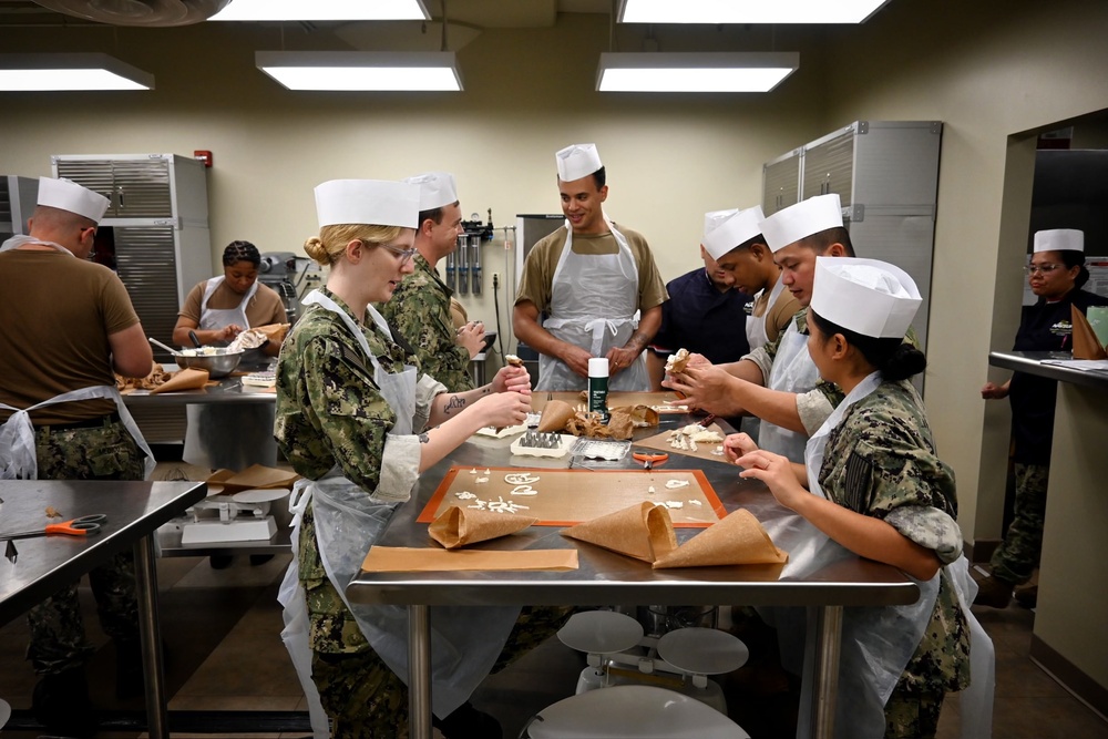 Sailors gather as they learn how to make icing and create icing pipes.