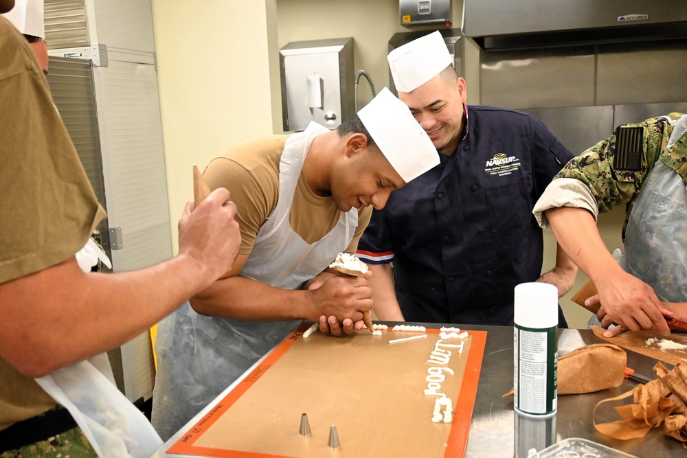 CSSN Albert Velasquez from USS John Canley (ESB-6), demonstrates his cake border technique to CS1 (SW/AW) Suriya Chuon.