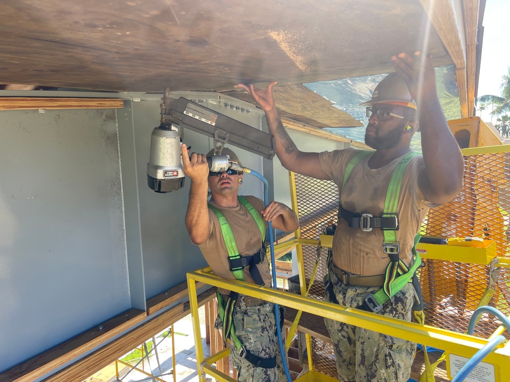 Seabees with Naval Mobile Construction Battalion 4 secure soffit to the Richardson Multipurpose Facility onboard U.S. Army Garrison - Kwajalein Atoll.
