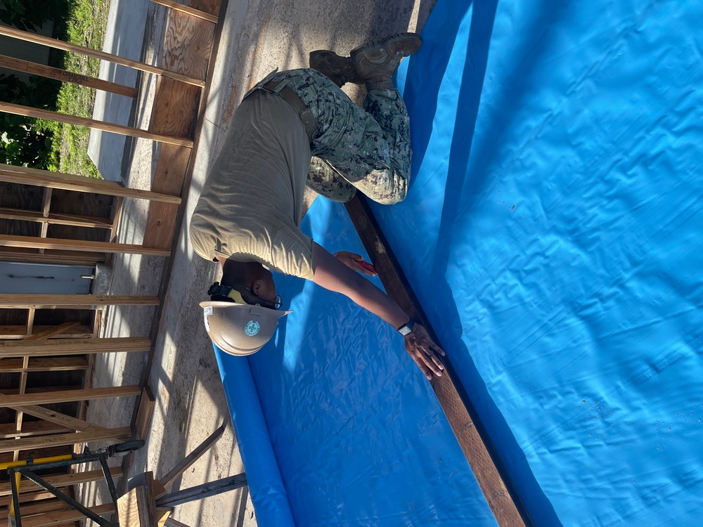 Builder 3rd Class Darren Levine, cuts strips of vapor barrier