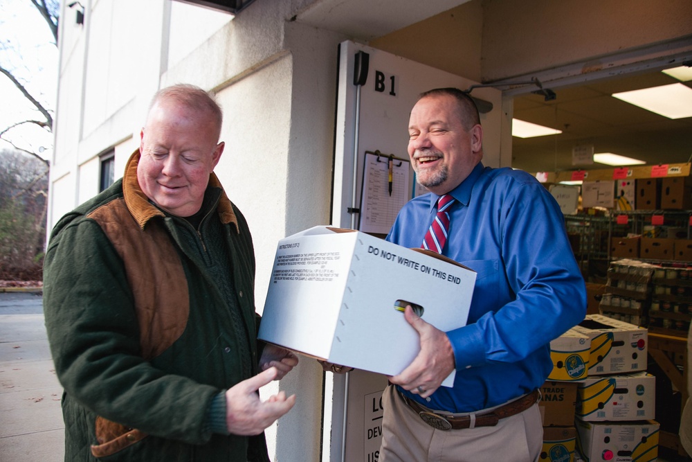 Joe Cunningham hands Keith Jackson, Deputy to the Garrison Commander, a box of canned goods at the food drive drop off.